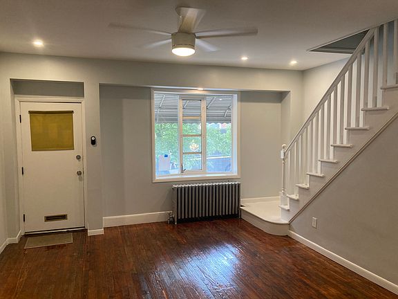 The living room features original, refinished hard wood floors, an open staircase, and a lovely front bay window with plenty of room for plants and other decorations.