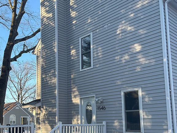 Back of house with wrap around deck next to private parking pad.