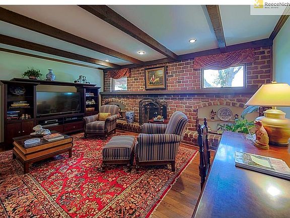 COZY UP IN YOUR BEAMED CEILING LIVING ROOM WITH FEATURE FIREPLACE AND BRICK BUILT-INS