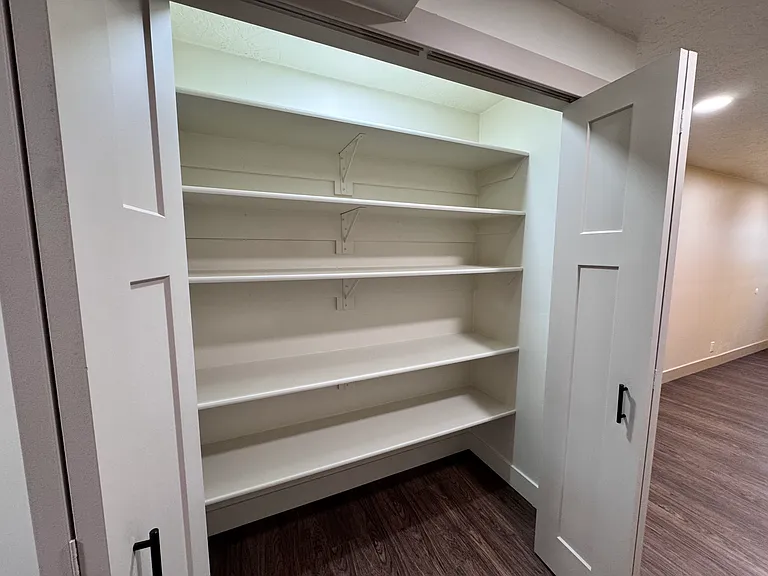 Spacious pantry with built-in shelving, offering ample storage and easy organization.