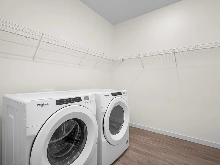 Spacious laundry room with modern washer and dryer, featuring sleek shelving and elegant flooring. Spacious laundry room with modern washer and dryer, featuring sleek shelving and elegant flooring.