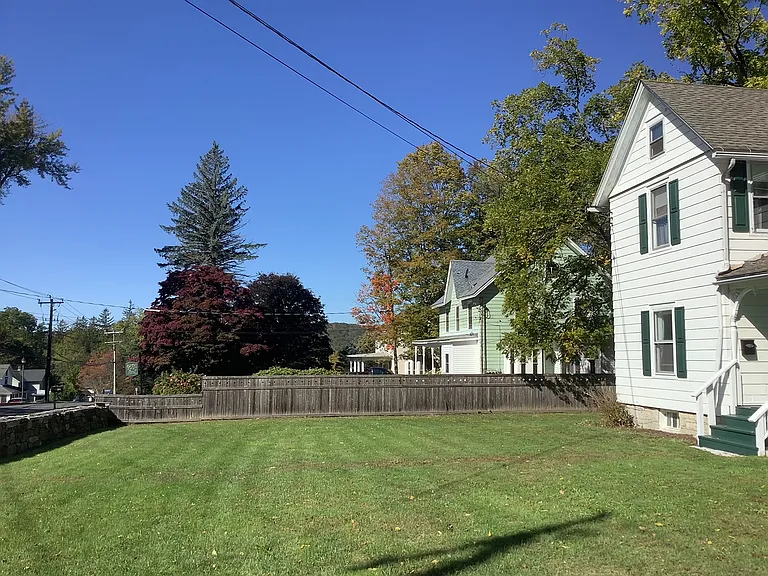 View of neighbors from front yard. Apartment is upstairs of house @ right. A small, attractive regional hospital is beyond.
