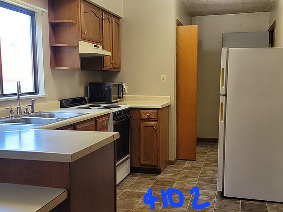 Kitchen showing breakfast bar, sink, cabinets, range, fridge and to the rear, the laundry closet with washer and dryer.