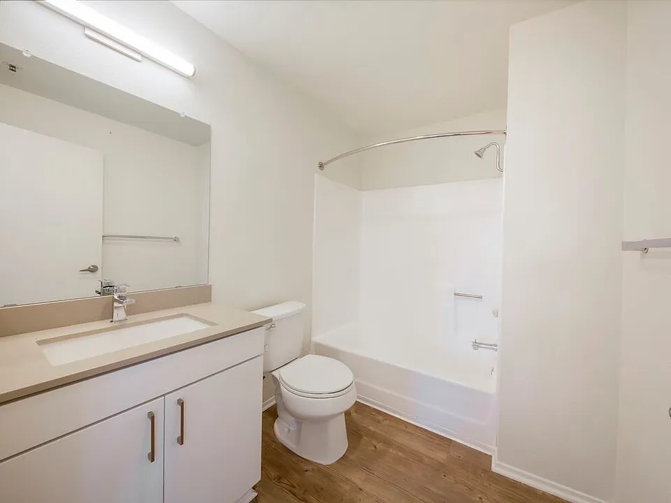 Renovated Package Bath with white cabinetry, grey quartz countertop, and hard surface flooring