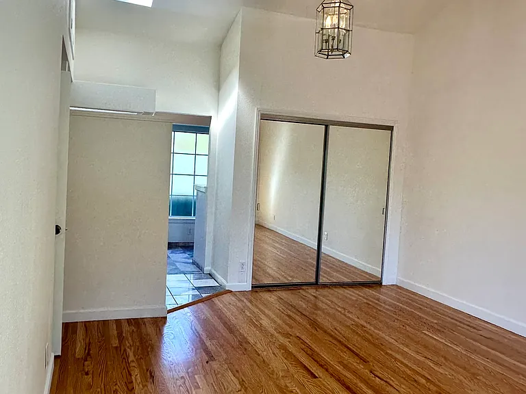Expansive primary bedroom with high ceiling and skylight