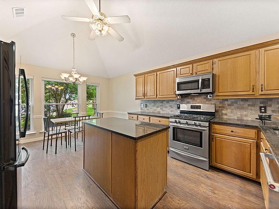 Kitchen with generous cabinet storage, central island prep space, and stainless-steel range/microwave near eat-in area.