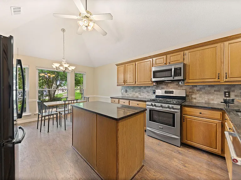 Kitchen with generous cabinet storage, central island prep space, and stainless-steel range/microwave near eat-in area.