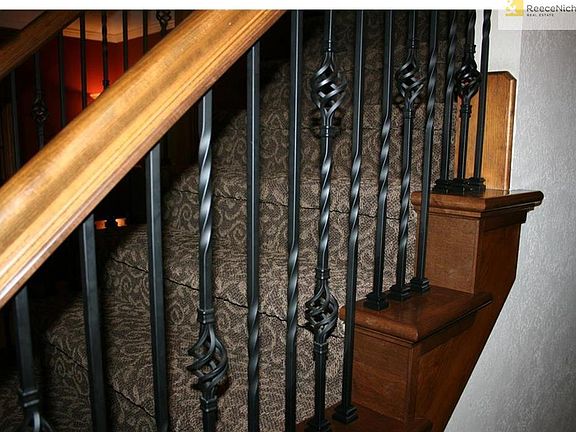 Designer carpet flows up the staircase with iron spindles.