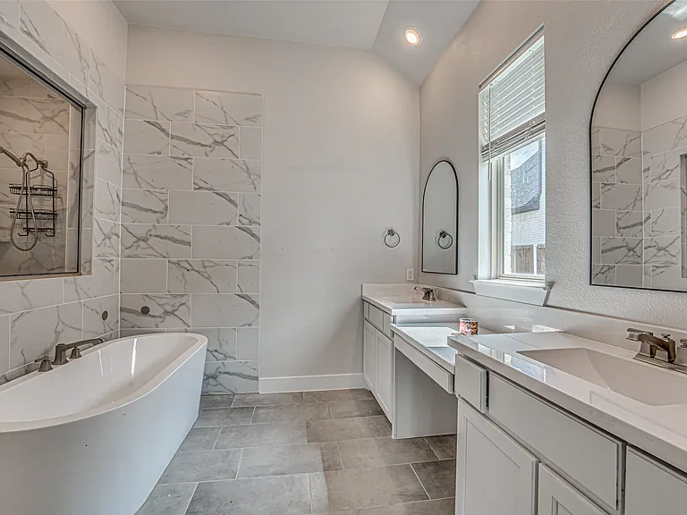 Freestanding soaking tub with brushed nickel fixtures, complemented by a large walk-in shower featuring marble-look tile surround and built-in shelving