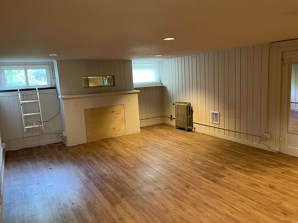 Living area with functioning radiator and two supplemental wall heaters. Fireplace is closed off.