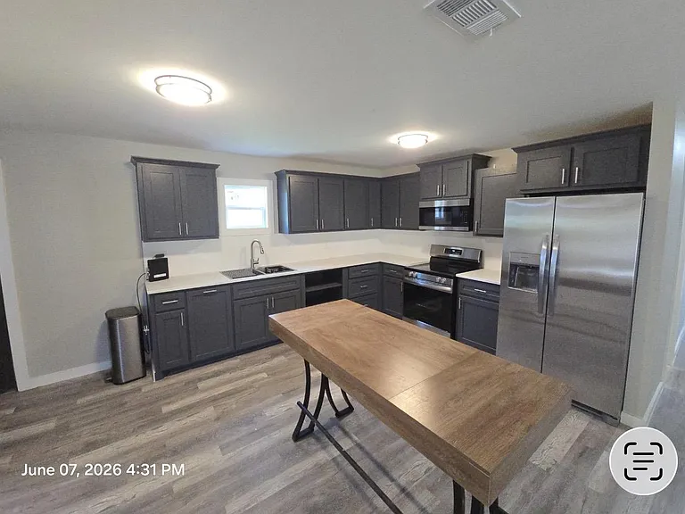 Spacious U-shaped kitchen with ample cabinet storage, generous counters, and stainless steel appliances plus a prep table.