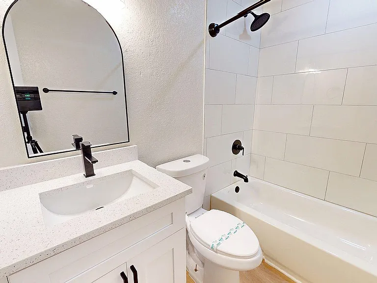 Elegant bathroom showcasing a modern white sink, sleek black fixtures, and a pristine shower-bath combo for a luxurious experience.
