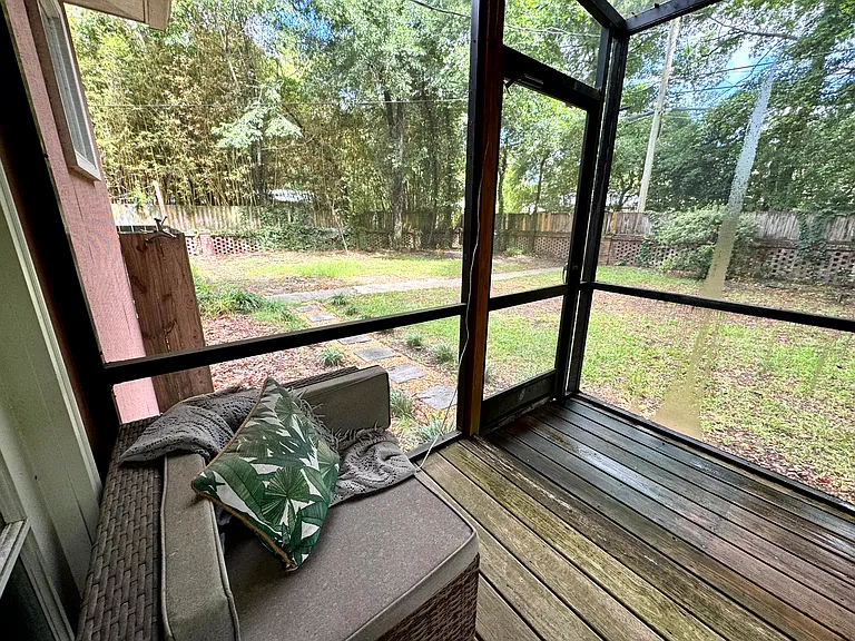 Screened-in deck off of primary bedroom overlooks the fenced-in backyard