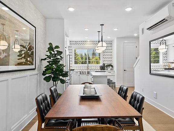 A modern and stylish dining room with a long wooden table, black chairs, and various decorative elem