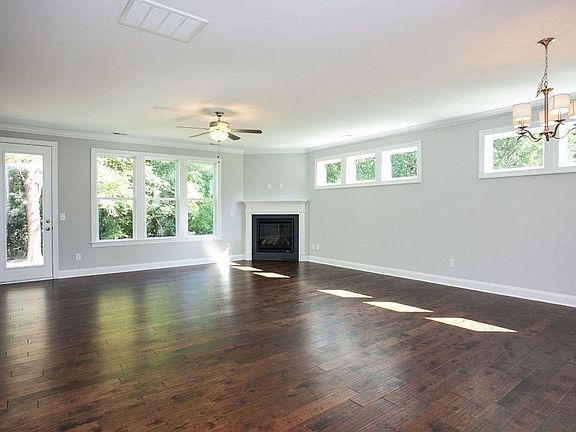 Living room/dining room. There are blinds on the larger windows and the door. The door leads to a concrete patio and a green backyard.