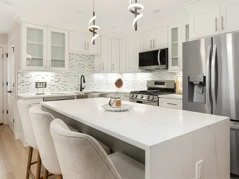 Gourmet kitchen goals: A stunning open layout featuring a massive granite island, custom cabinetry, and all-new stainless steel appliances.