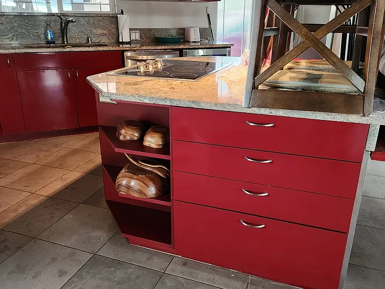The kitchen from the side door leading outside. Old chairs are pictured.