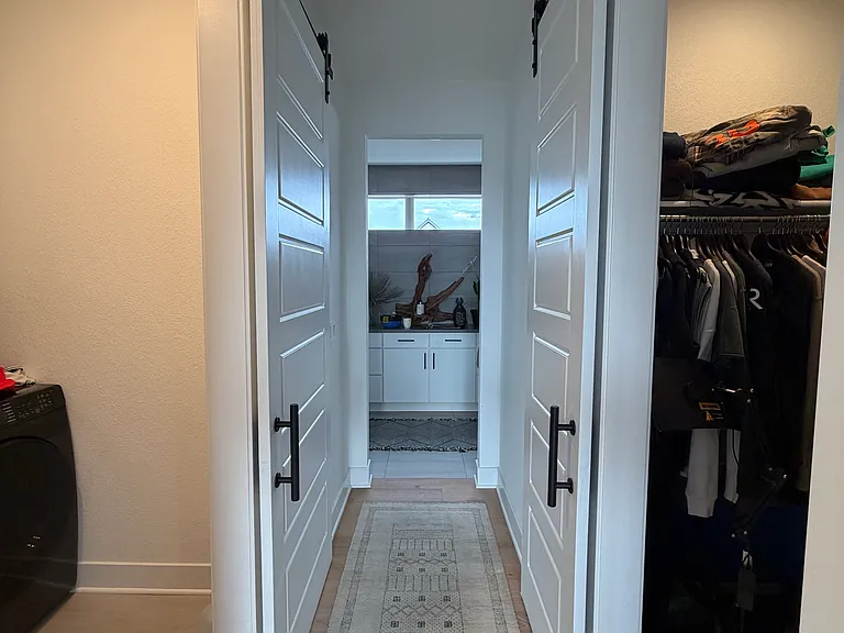 Primary Hallway from bedroom to bathroom. Walk-in closet, laundry room