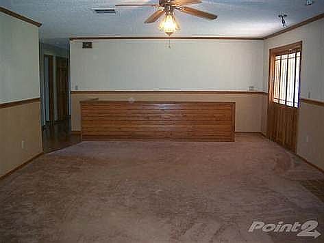 Large living room w/ wood-burning fireplace, ceiling fan, stairway to basement, and opens to sunroom