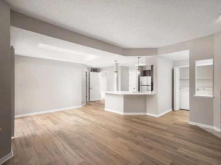 Spacious open-plan apartment with elegant hardwood floors, modern kitchen island, and ample natural light.