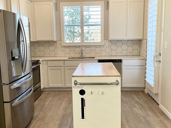 Kitchen with island that can be moved or removed and full-size refrigerator