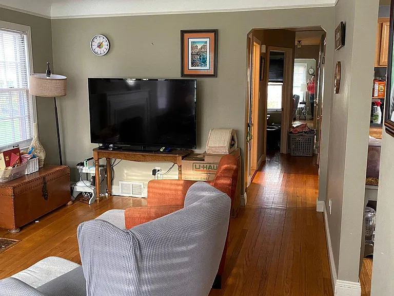 Living room view shows hallway leading to two bedrooms. Dining room and kitchen are to the right.