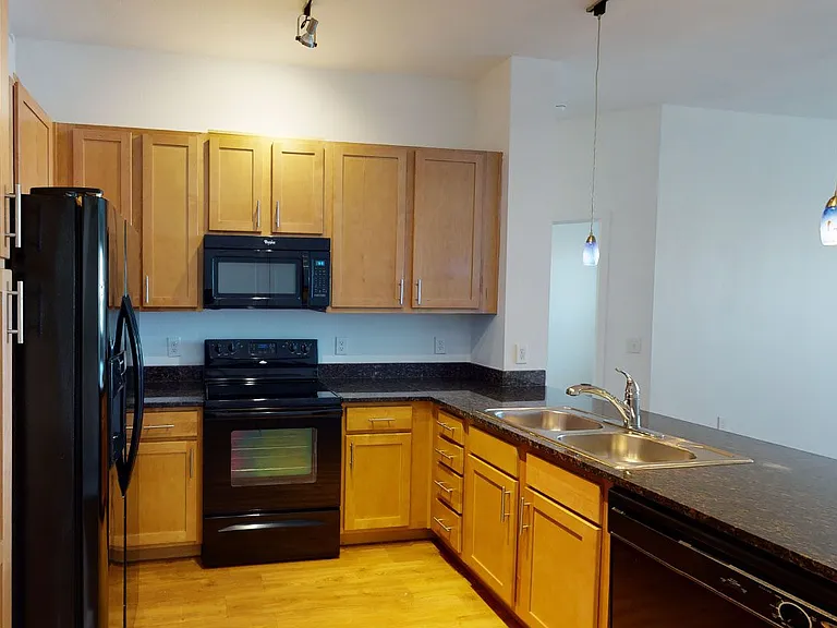 Apartment kitchen with granite countertops and wood-style flooring.