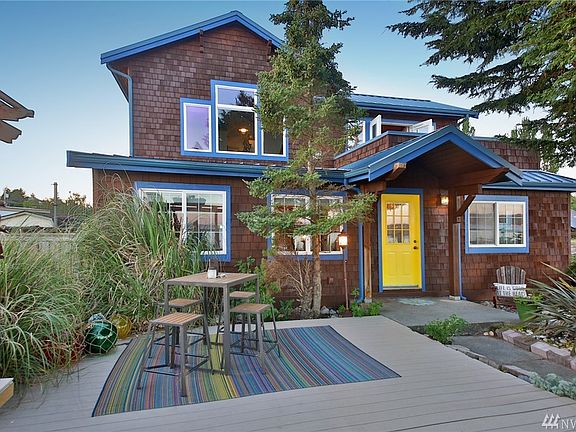 View from the beach with expansive deck & courtyard. The yellow door is your main entrance from beachside.  Windows to the left belong to the living room, to the right-dining room.  Large windows above - Master Suite.