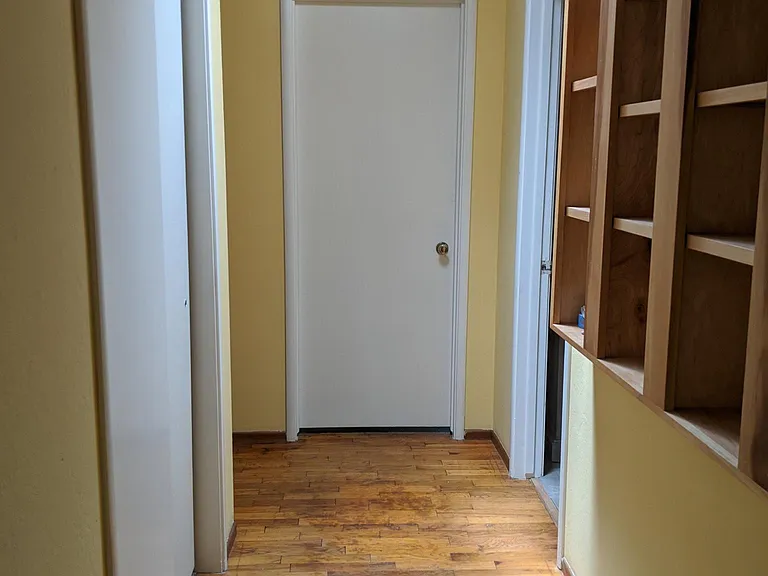 Hallway has a linen closet on one side and built-in bookshelves on the other.
