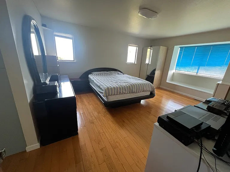 Bed area in primary suite, showing windows facing north and east.