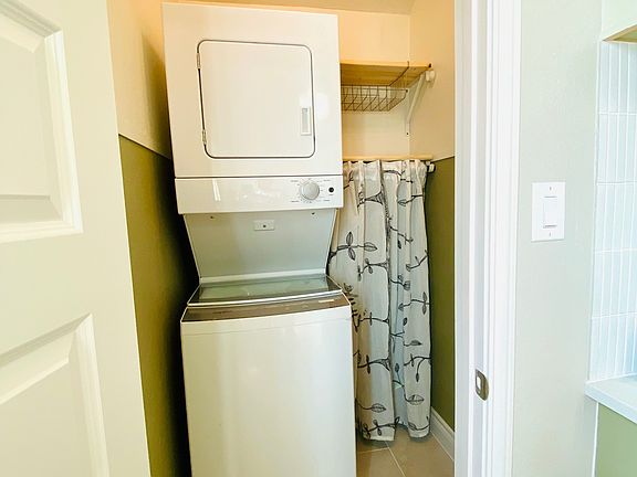 stackable washer dryer,with storage shelves,the vacuum and mop is hidden behind the curtain