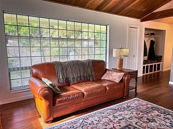 Large front window near coat closet, rack, bench and shoe storage off hallway from front entry.>