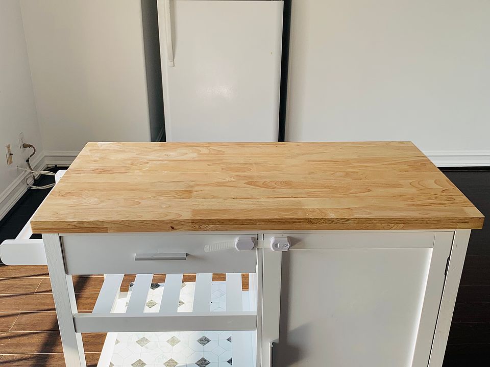 Fridge tucked against the wall with kitchen island in front.