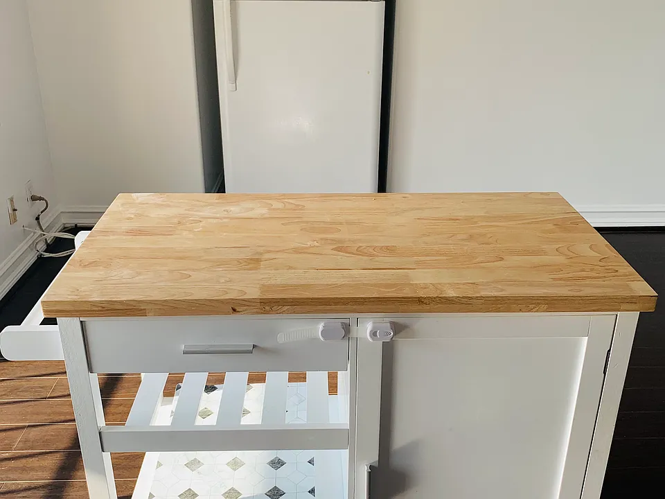 Fridge tucked against the wall with kitchen island in front.