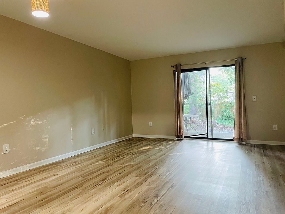 Ample living room with gorgeous floors, new paint, drapes overlooking shaded wooded area