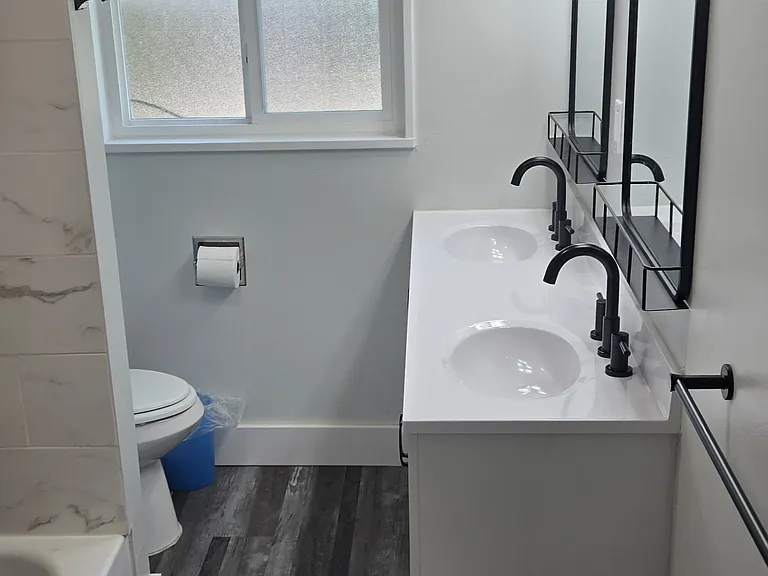 Fully renovated bathroom with two sinks and mirrors