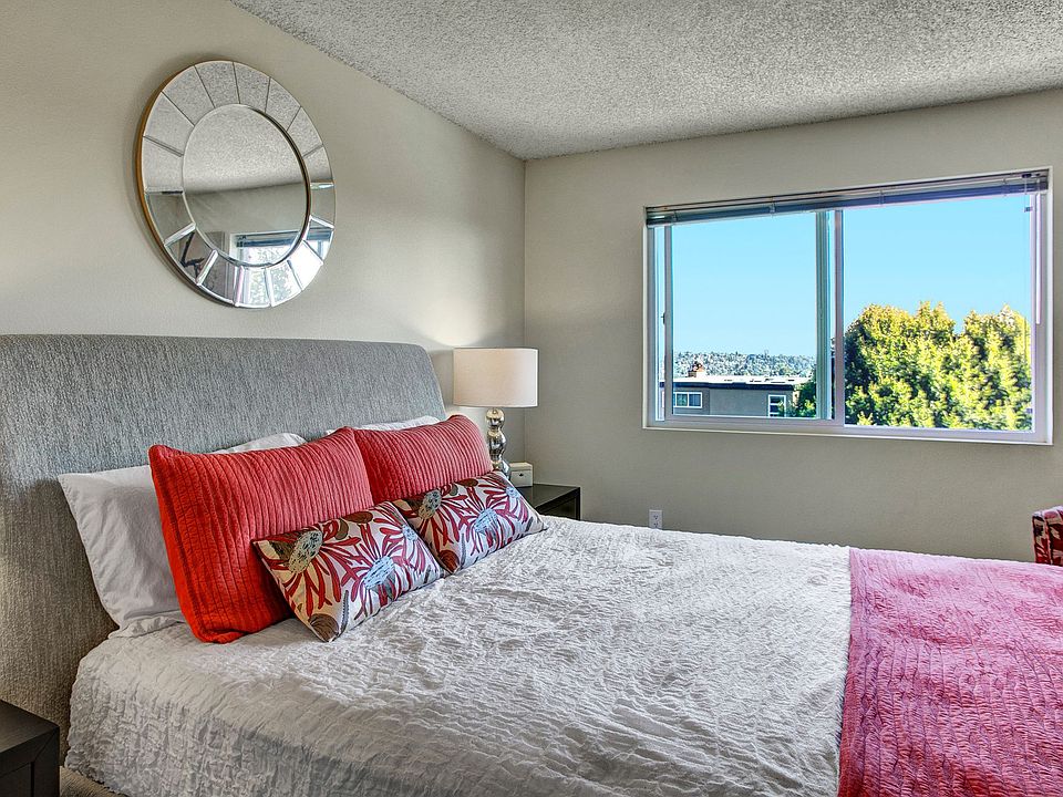 A bedroom with two nightstands and a bed with a large window overlooking the property