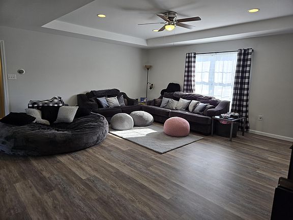 Living room with couch, loveseat, 8-foot chill sac, 70" TV, faux fur rug, hand crocheted foot rests, tons of throw pillows, ceiling fan, etc.