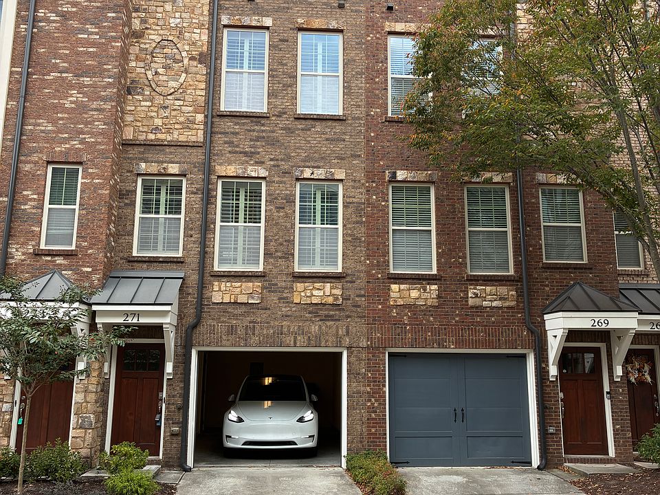 Townhouse with the garage door open. Entrance is to the left. Second car can be parked in driveway.