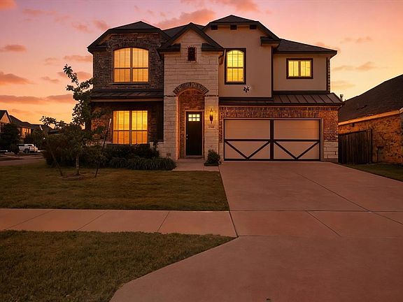 View of front of property featuring a standing seam roof, stone siding, a metal roof, concrete driveway, and a garage