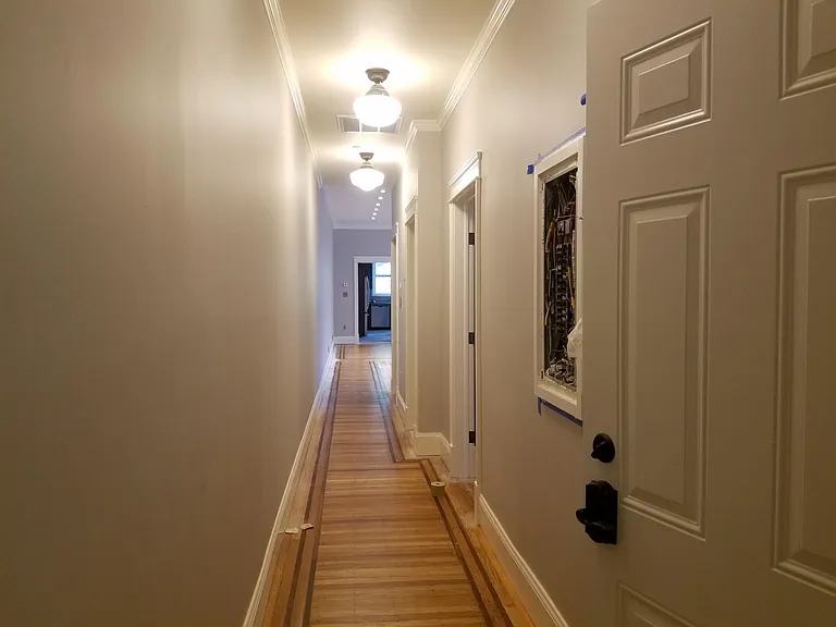 Entry hall with a security camera to view door with monitor /intercom and door release. Original hardwood floor with walnut detailing. Energy monitors and keyless apartment entry.