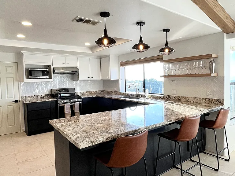 A large kitchen with a U-shaped island offers plenty of prep, eating, and hangout space. Not pictured but available is a modern stainless steel refrigerator and dishwasher