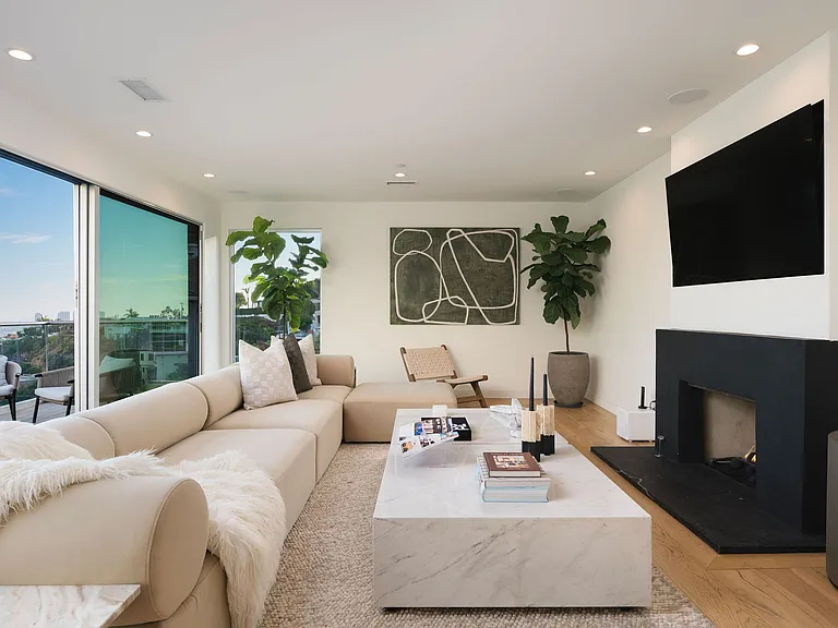 1st floor living room lounge with floor to ceiling glass windows, balcony with seating, smart TV and fireplace.