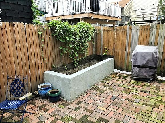 Spacious rear Courtyard features original red brick, built-in Garden, privacy fence, and walkway to Sidney St!