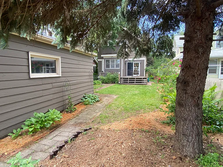 Additional yard/garden space under a large pine tree in the backyard.