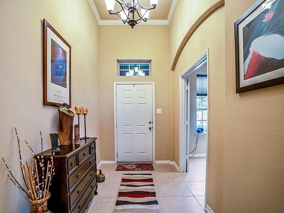 Welcoming entry with high ceilings framed with crown molding and chandelier.