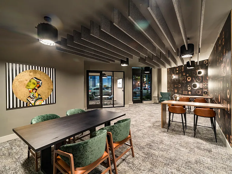 A flexible meeting and work space with shared tables, acoustic details, and a relaxed setting suited for collaboration or quiet focus.