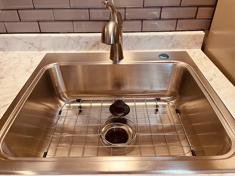 Large stainless steel sink with protective grate. Garbage disposal.