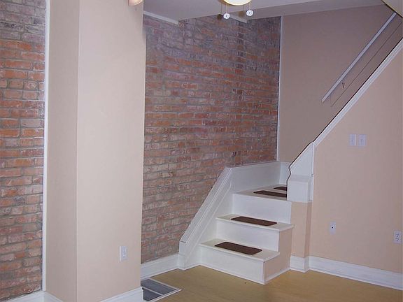 Living Rm Exposed Brick Wall & Stairs to 2nd fl