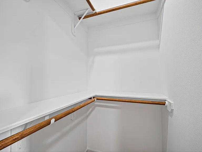 Walk-in closet with wraparound shelving and dual hanging rods for efficient organization and easy-access storage.